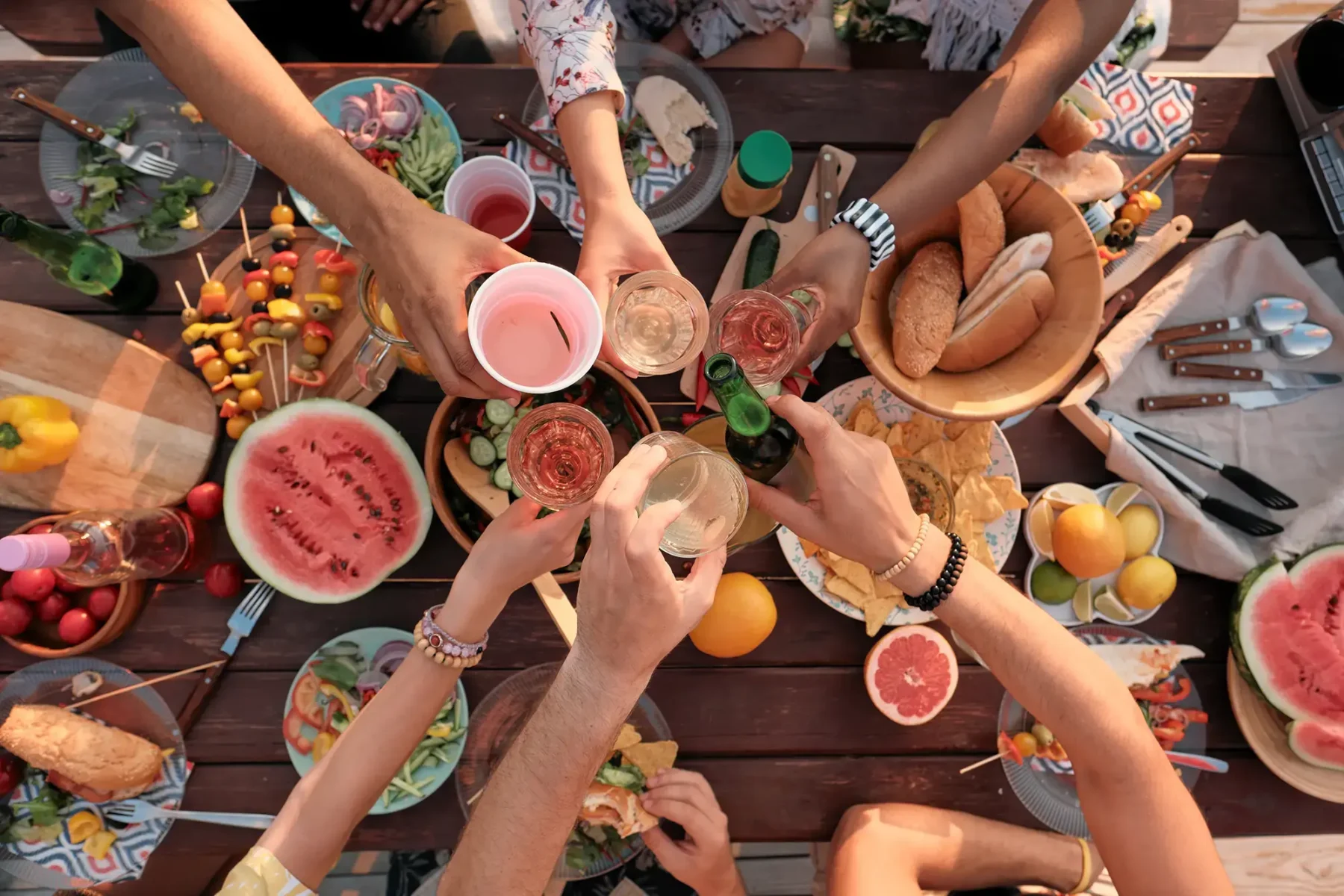 Friends having an outdoor meal clinking drinks together