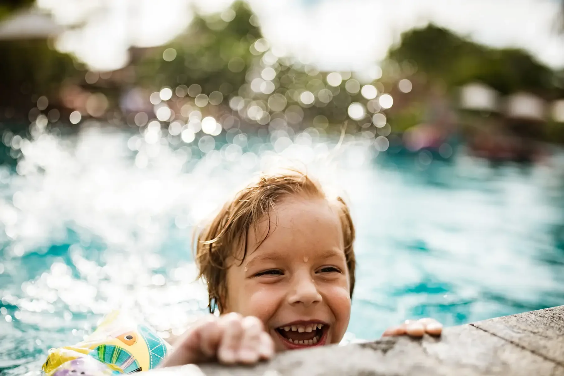 young boy in a pool peeking over the side